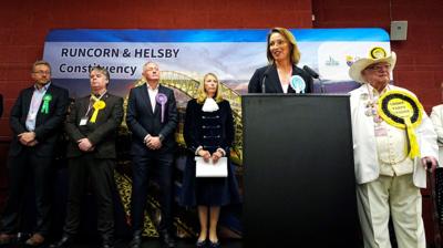 Wide image showing Sarah Pochin at a podium giving her victory speech with other by-election candidates standing behind her.