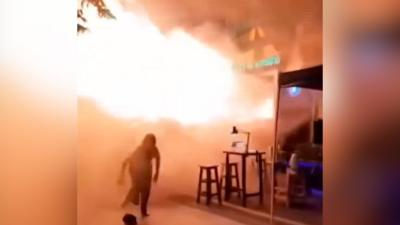 Someone runs from flames erupting from a bar doorway