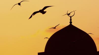 silhouette of a mosque and birds flying past