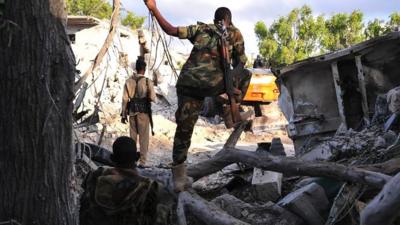 Somali security forces walk at the scene of a blast on October 29, 2017, a day after two car bombs exploded in Mogadishu.