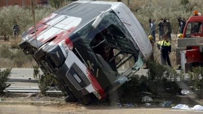 The wreckage of a bus is lifted by a crane