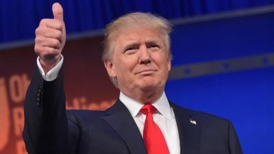 Donald Trump flashes the thumbs-up as he arrives on stage for the start of the Republican presidential debate 6 August 2015
