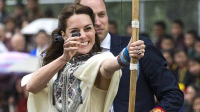 The Duchess of Cambridge fires an arrow, as the Duke of Cambridge looks on