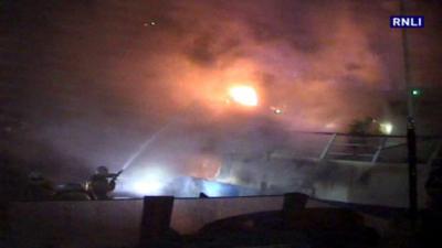 Firefighters tackle a blaze on a fishing boat