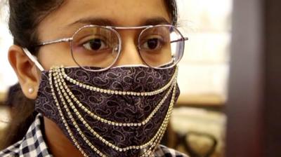 A girl wearing a mask with rows of beads sewn on it