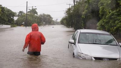 A man wades through flood water up to his thighs in Townsville