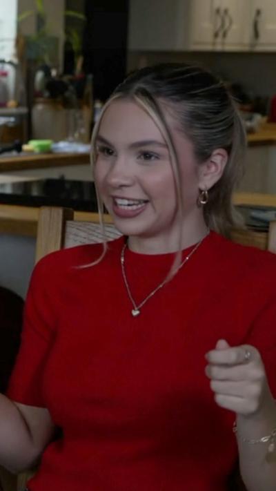 Sioned Cray is in a red top and wearing a silver necklace. She has blonde hair tied back except for two strands at the front