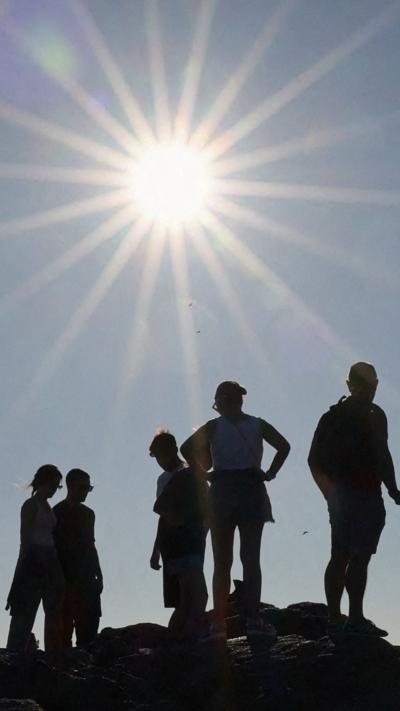 People seen in silhouette in front of the Sun
