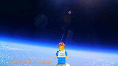 A lego figure is wearing a blue and white outfit and is floating in space