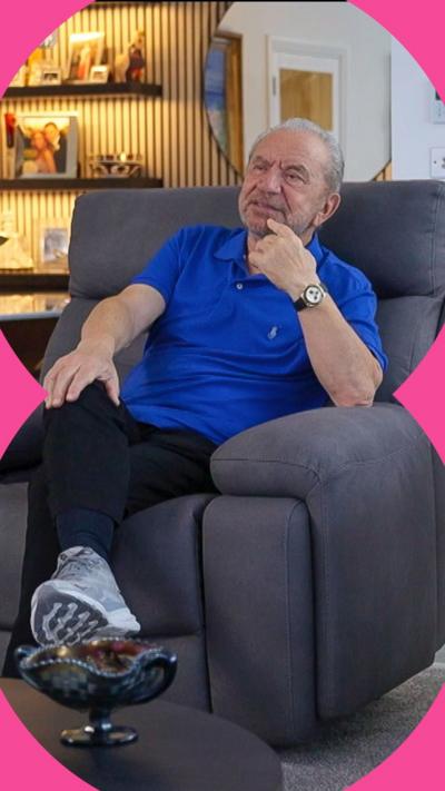 Lord Sugar sitting on a grey chair and looking pensive