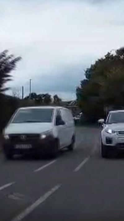 A white van overtaking a white car on a residential street