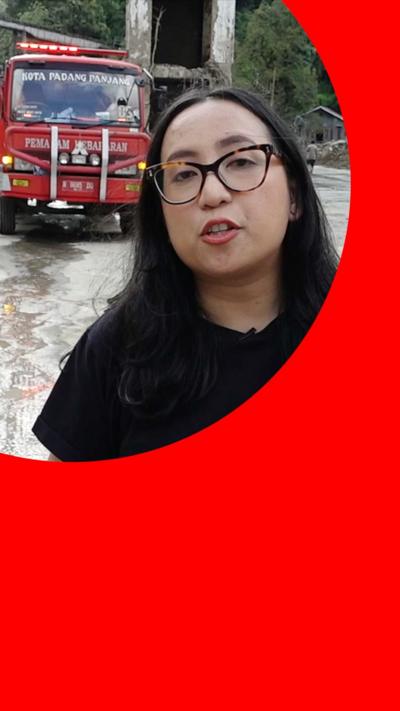 Reporter stands in front of fire engine at scene of flooding