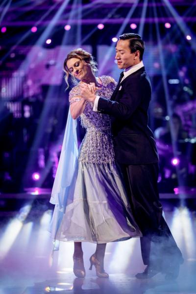 Two ballroom dancers. A woman in a violet dress and man in black suit