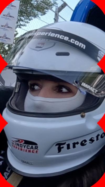 BBC reporter in a sports car wearing a helmet.