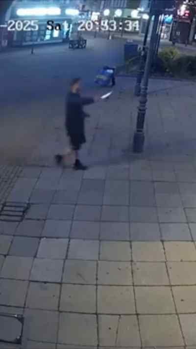 A CCTV still of a man waving a knife around on a street