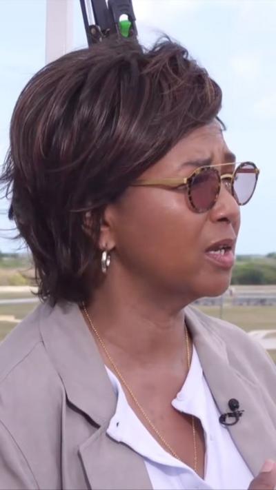 Mae Jemison speaks to the BBC wearing sunglasses a tan suit and white shirt.