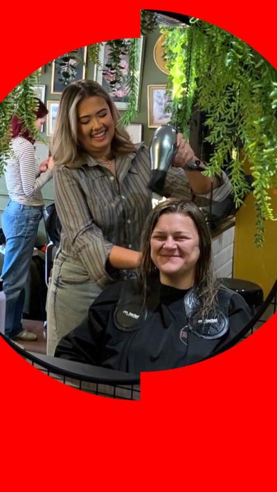 A hairdresser tends to a customer's hair in a salon