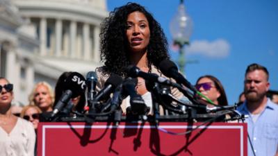 Lisa Phillips speaks into a mic in front of capitol hill in Washington.