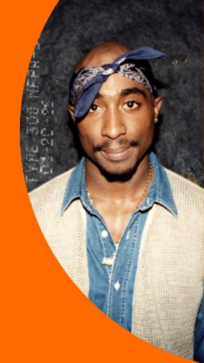 Tupac Shakur wearing a blue bandana and a blue and white shirt.