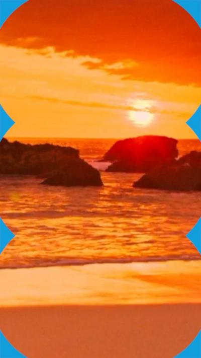 Deep orange sunset over the sea with large rocks in the water