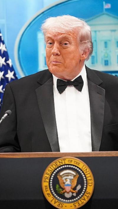 Trump in tuxedo at podium looking to left