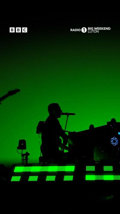 Coldplay at Radio 1 Big Weekend festival. The stage is lit up with colour.