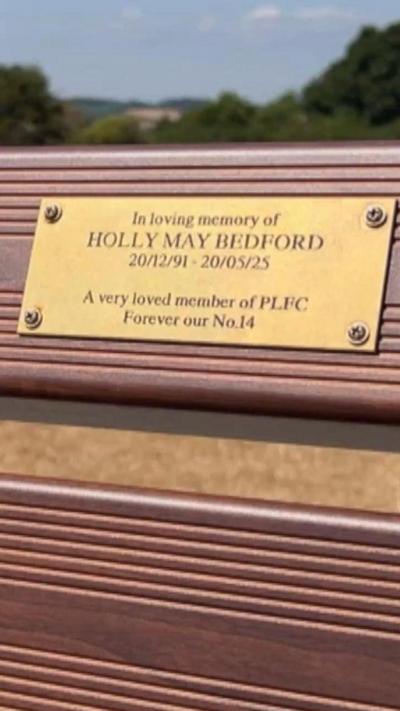 A close up of a plague on a bench in memory of Holly may Bedford