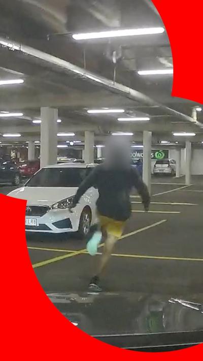A screenshot of a video of a man running in a car park, his head blurred.