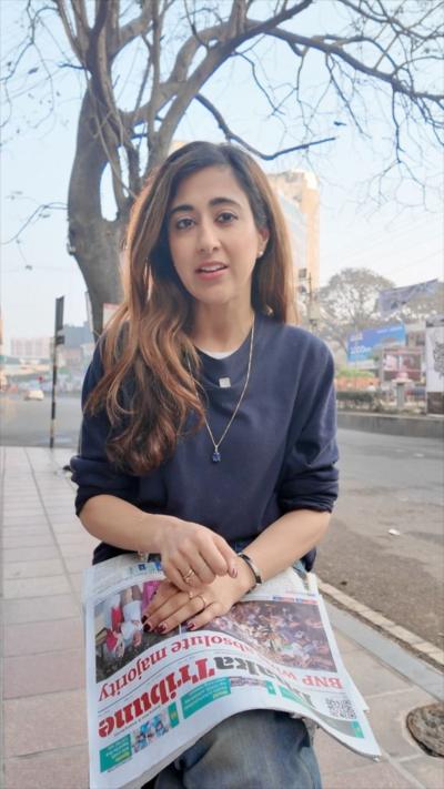 A woman rests a newspaper on her lap