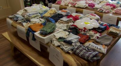 Boxes filled with children's clothing on a wooden table. 