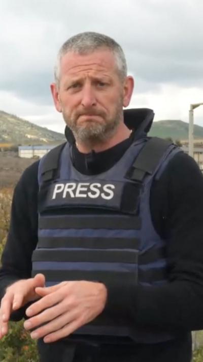 Jon Donnison wearing a Press vest speaking at the border