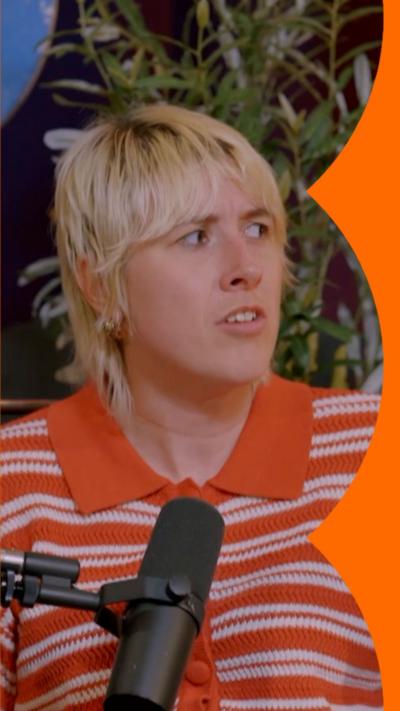 A woman with short, blonde hair sits in front of a microphone