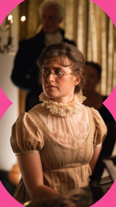 A woman looking to her right hand side, sits at a piano wearing a beige dress.