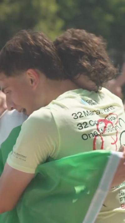 Jordan and Cian Adams embrace wrapped in an Irish tricolour flag as they finish their 33 marathon challenge.