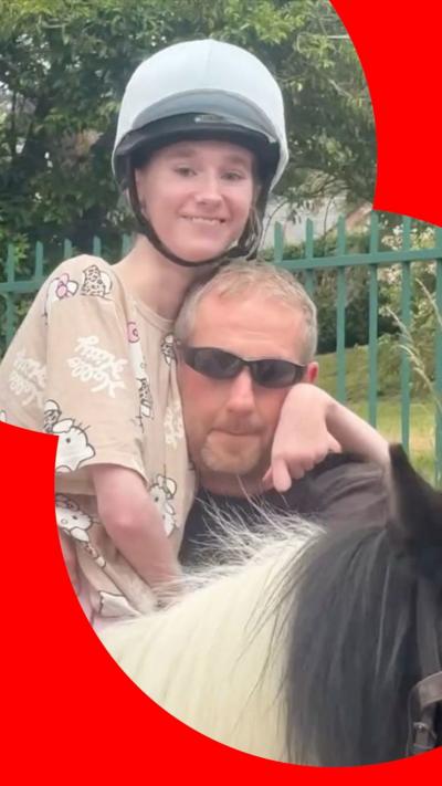 Jessica on a horse. She is smiling and being held up by her dad