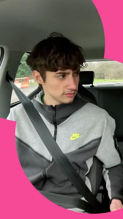 A boy in a grey hoody sitting in a car