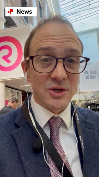 Chris Mason wearing a blue suit talking to a camera in selfie mode