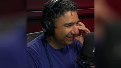 Nick Mohammed smiles in front of a microphone