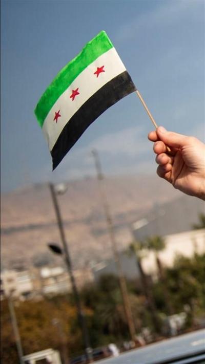 A hand holding a Syrian flag