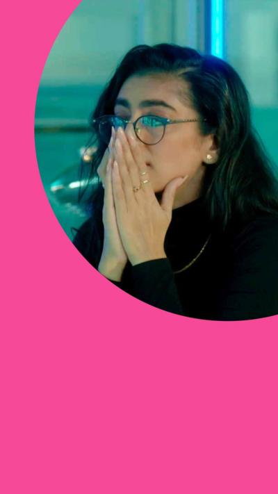 Woman with long hair and glasses pensively holds her hands over her nose.