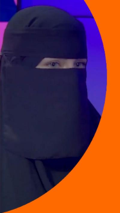 A woman wearing the niqab. She has a radio microphone in front of her.