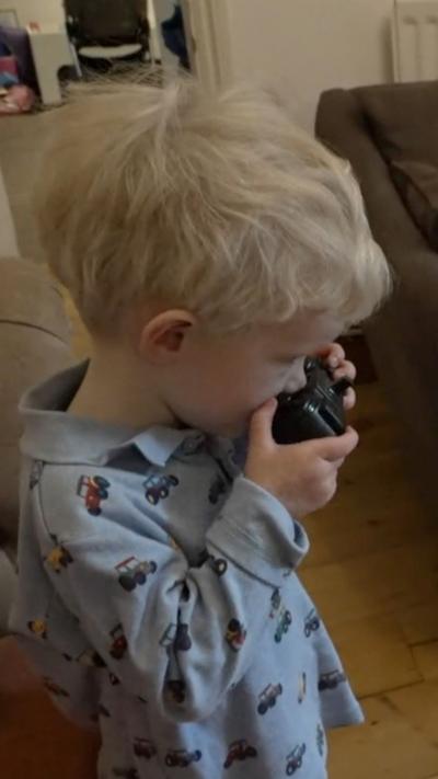 A young boy in blue pyjamas holding a remote controller.
