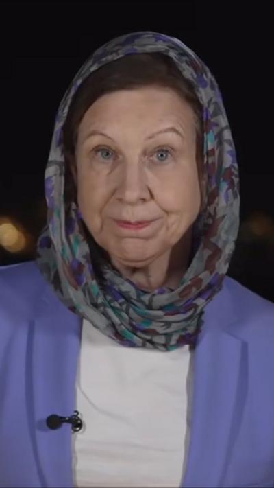 Lyse looks into the camera as she reports against a dark background