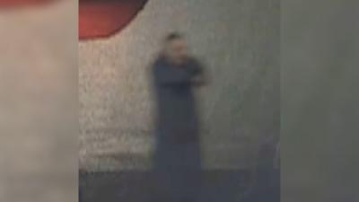 Grainy CCTV shows man standing in a dark street pointing a gun