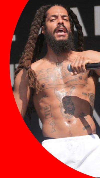 Bobby Vylan, wearing white shorts, holds a mic as he performs on stage on Saturday