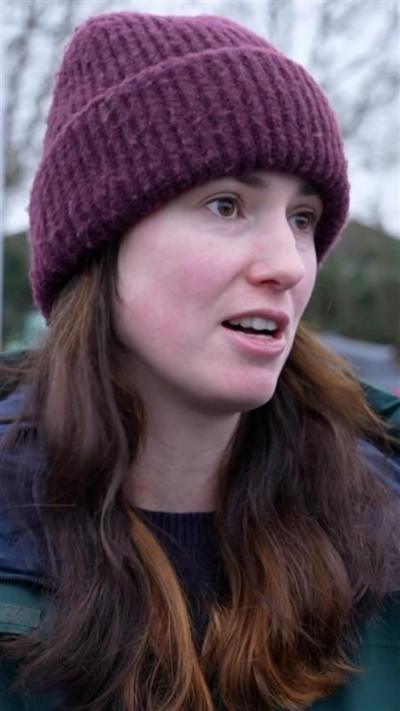 A woman with long brown hair in a purple hat and a coat