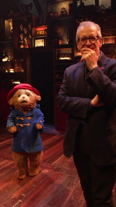 Paddington Bear and David Sillito stand on a stage.