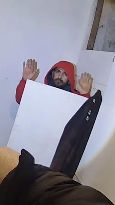 A man behind a cupboard door with his hands in the air