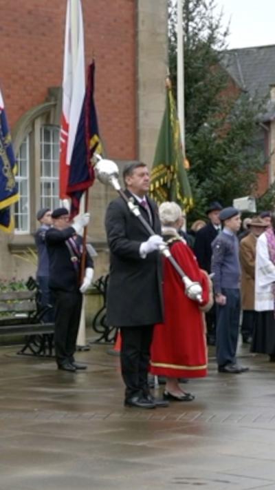 A man in a long coat holding a sceptre