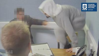 Man in grey outfit mid-lunge over table